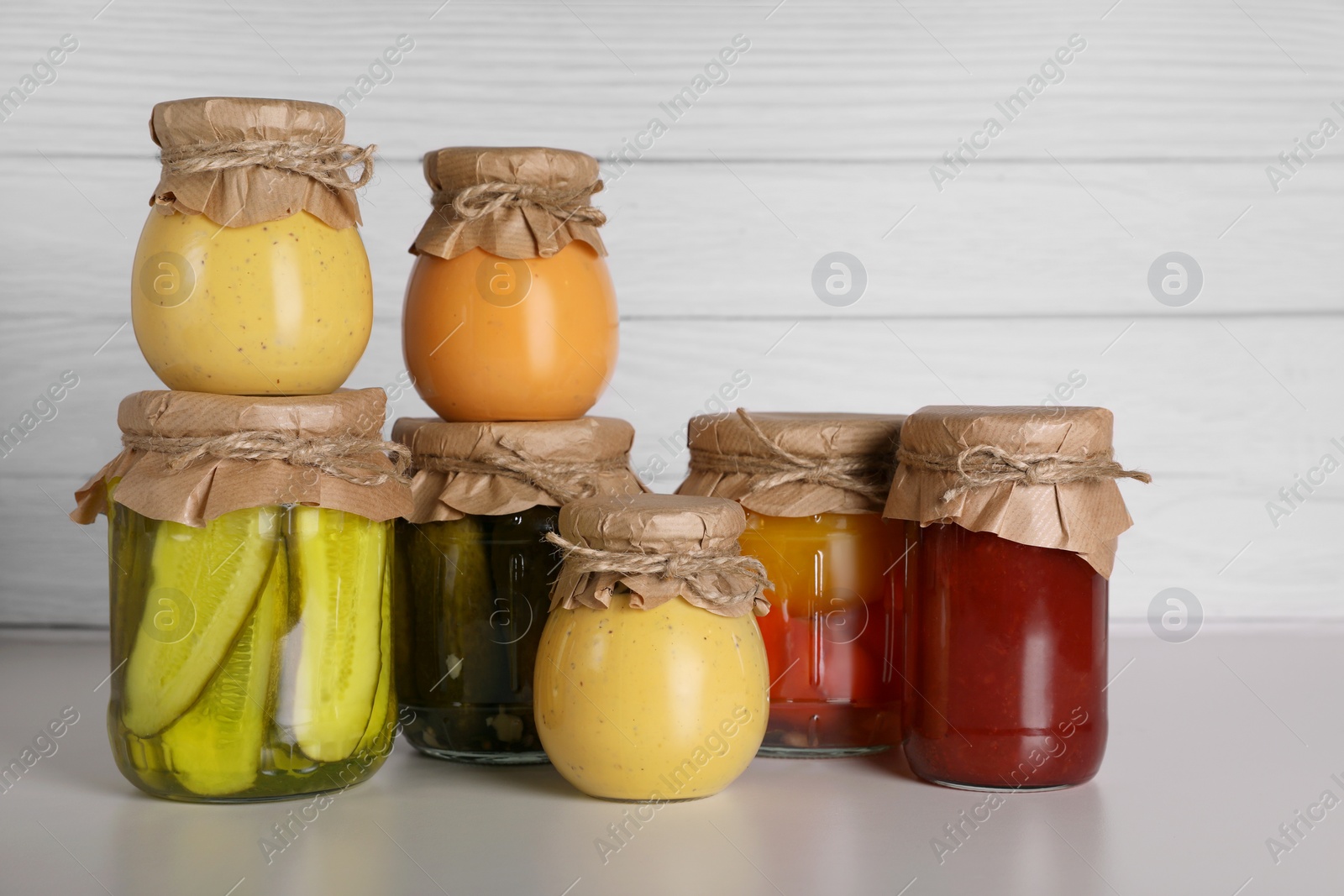 Photo of Many jars with different preserved products on light grey table
