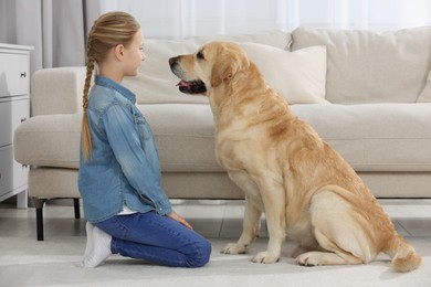 Photo of Cute child with her Labrador Retriever on floor at home. Adorable pet