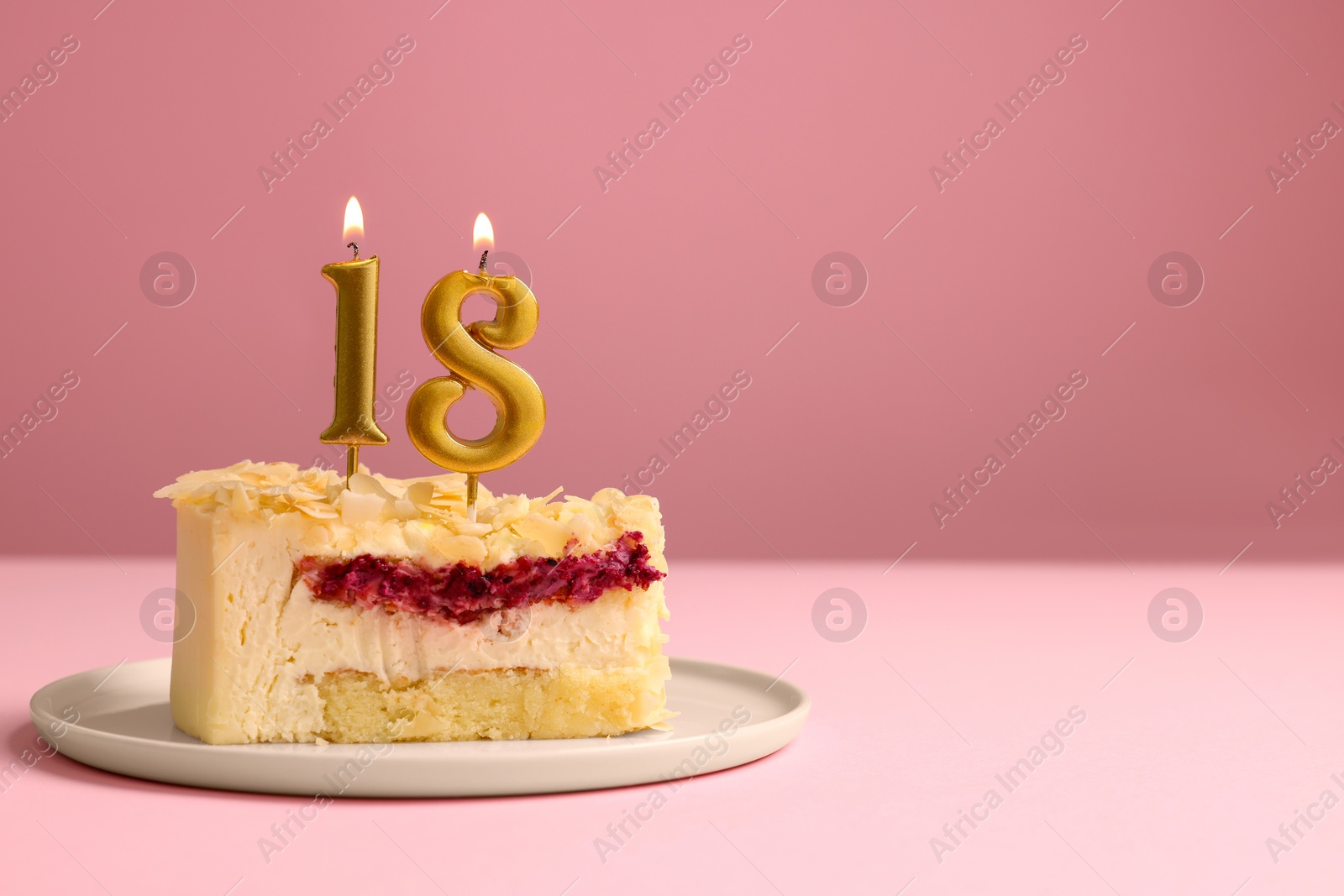 Photo of Coming of age party - 18th birthday. Delicious cake with number shaped candles on pink background, space for text