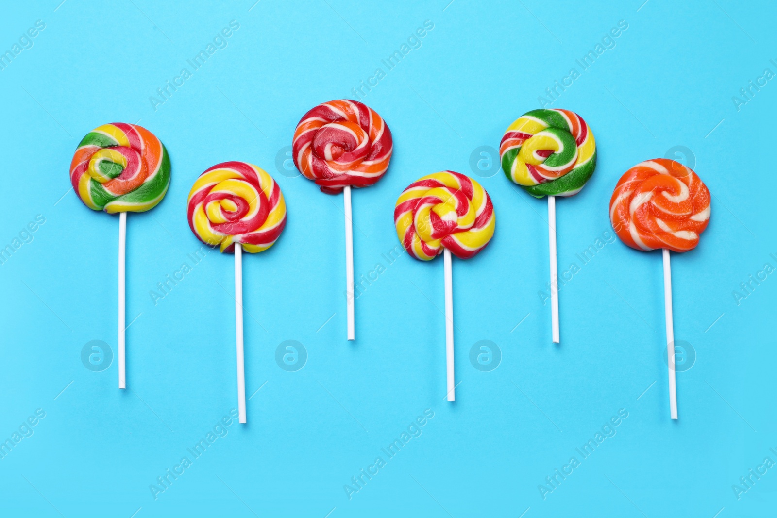 Photo of Sweet lollipops on light blue background, flat lay