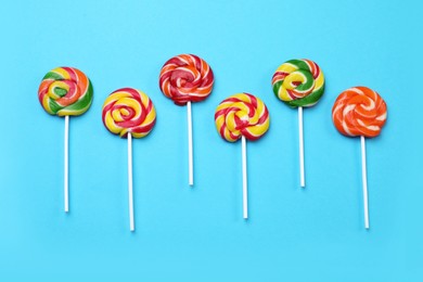 Sweet lollipops on light blue background, flat lay