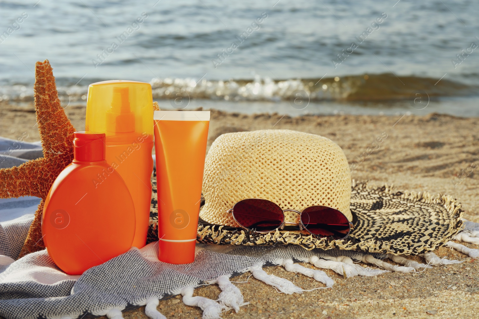 Photo of Sun protection products and beach accessories on blanket near sea