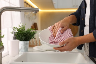 Photo of Woman wiping bowl with towel in kitchen, closeup