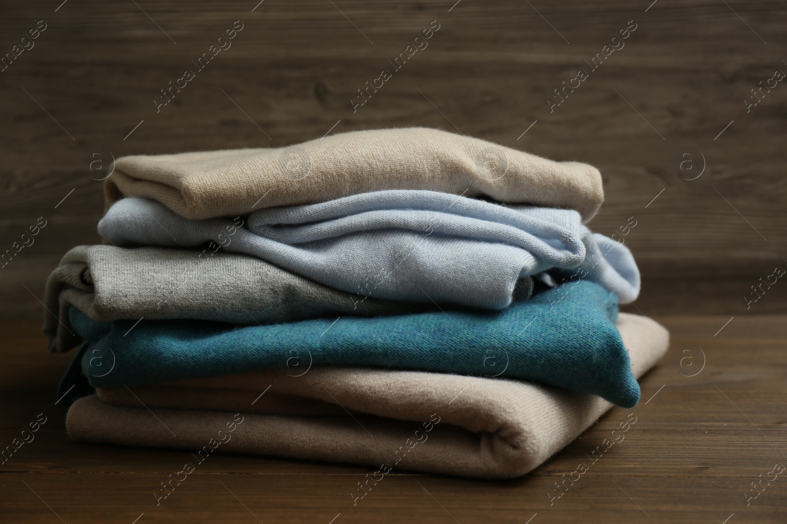 Photo of Stack of cashmere clothes on wooden background