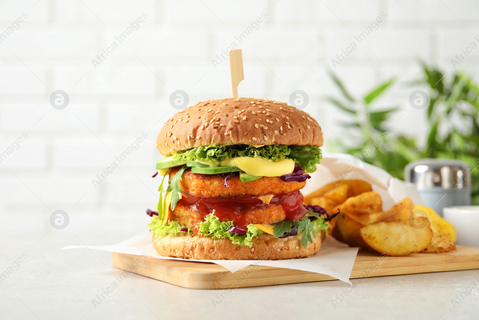 Photo of Vegan burger with carrot patties and fried potato served on table