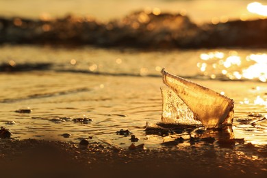 Used plastic cup on beach at sunset. Space for text