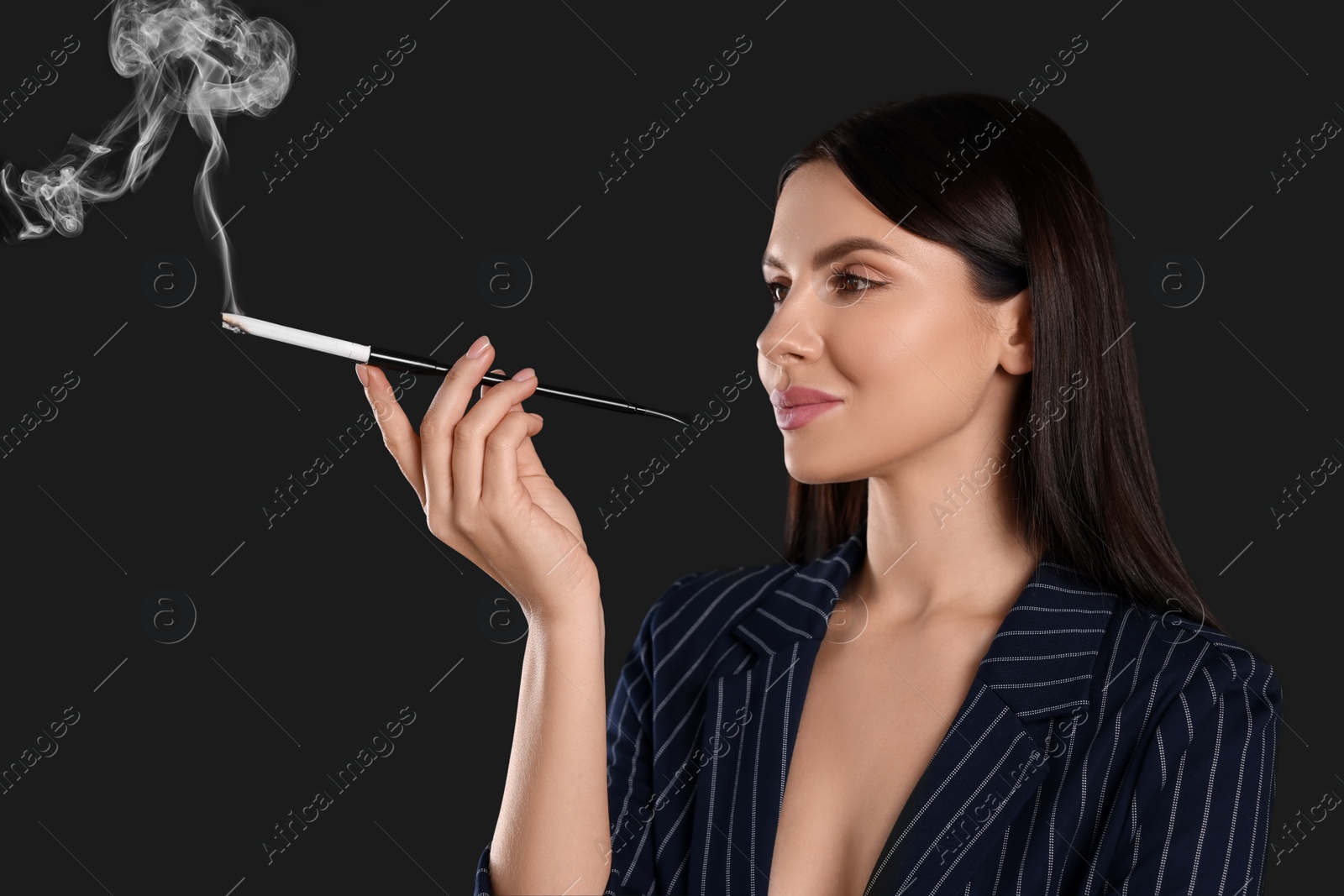 Photo of Woman using long cigarette holder for smoking on black background