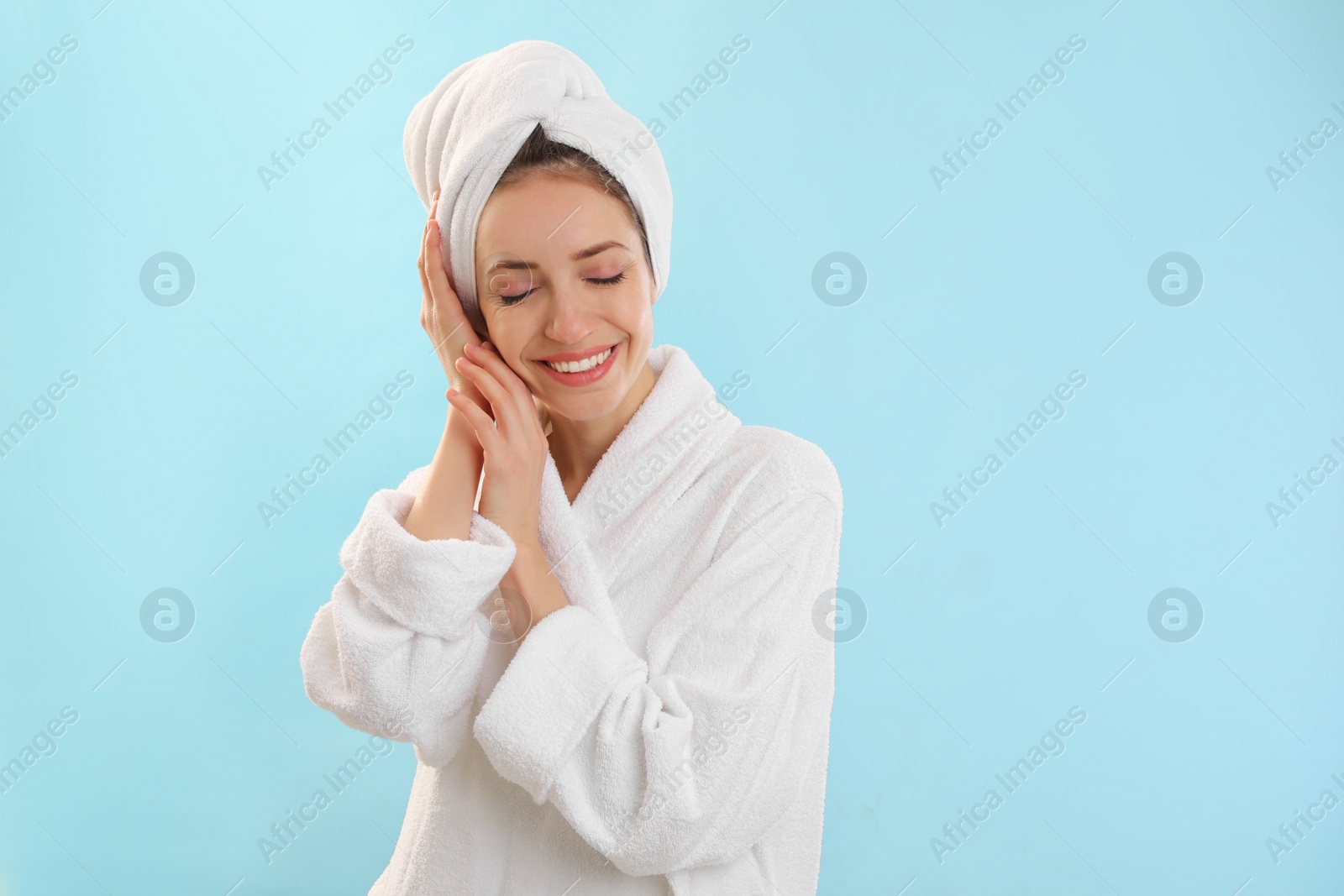 Photo of Beautiful young woman with hair wrapped in towel after washing on light blue background