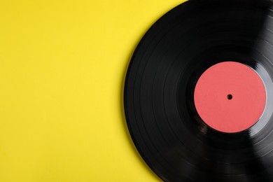 Photo of Vintage vinyl record on yellow background, top view. Space for text