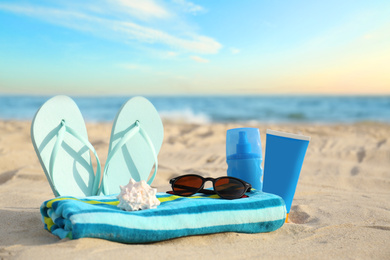 Different stylish beach objects and seashell on sand near sea