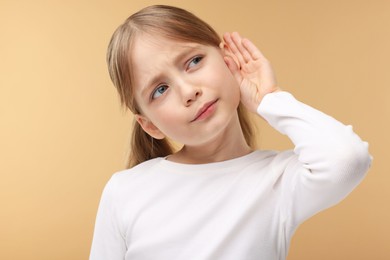 Photo of Little girl with hearing problem on pale brown background