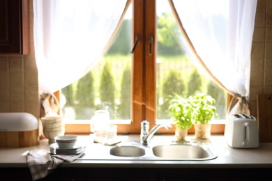 Photo of Blurred view of stylish kitchen interior with sink near window