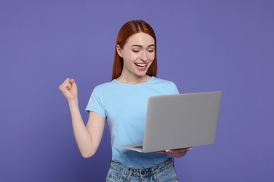 Happy young woman with laptop on lilac background