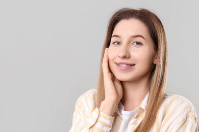 Portrait of smiling woman with dental braces on grey background. Space for text