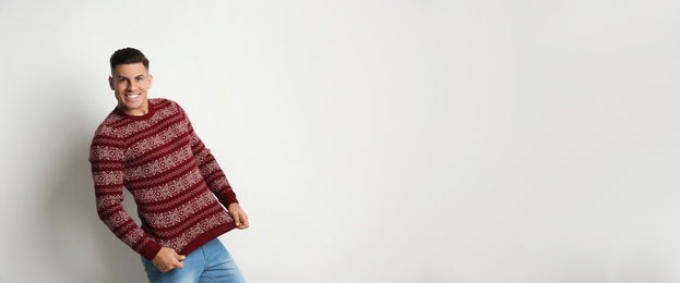 Photo of Happy man showing his Christmas sweater on white background, space for text
