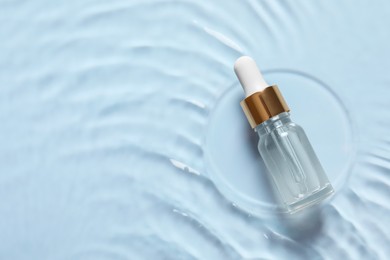 Bottle of cosmetic serum and water on light blue background, top view. Space for text