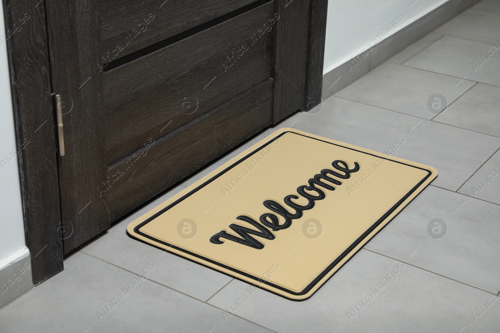 Photo of Beautiful beige doormat with word Welcome on floor near entrance