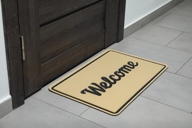 Photo of Beautiful beige doormat with word Welcome on floor near entrance