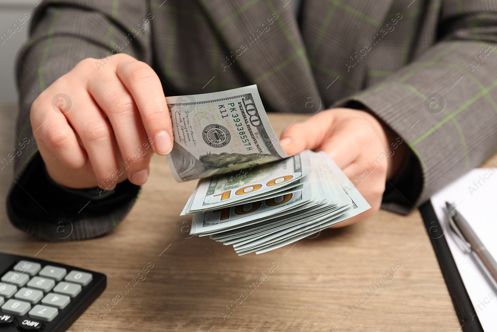 Photo of Money exchange. Woman counting dollar banknotes at wooden table, closeup