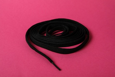 Photo of Black shoe lace on pink background. Stylish accessory