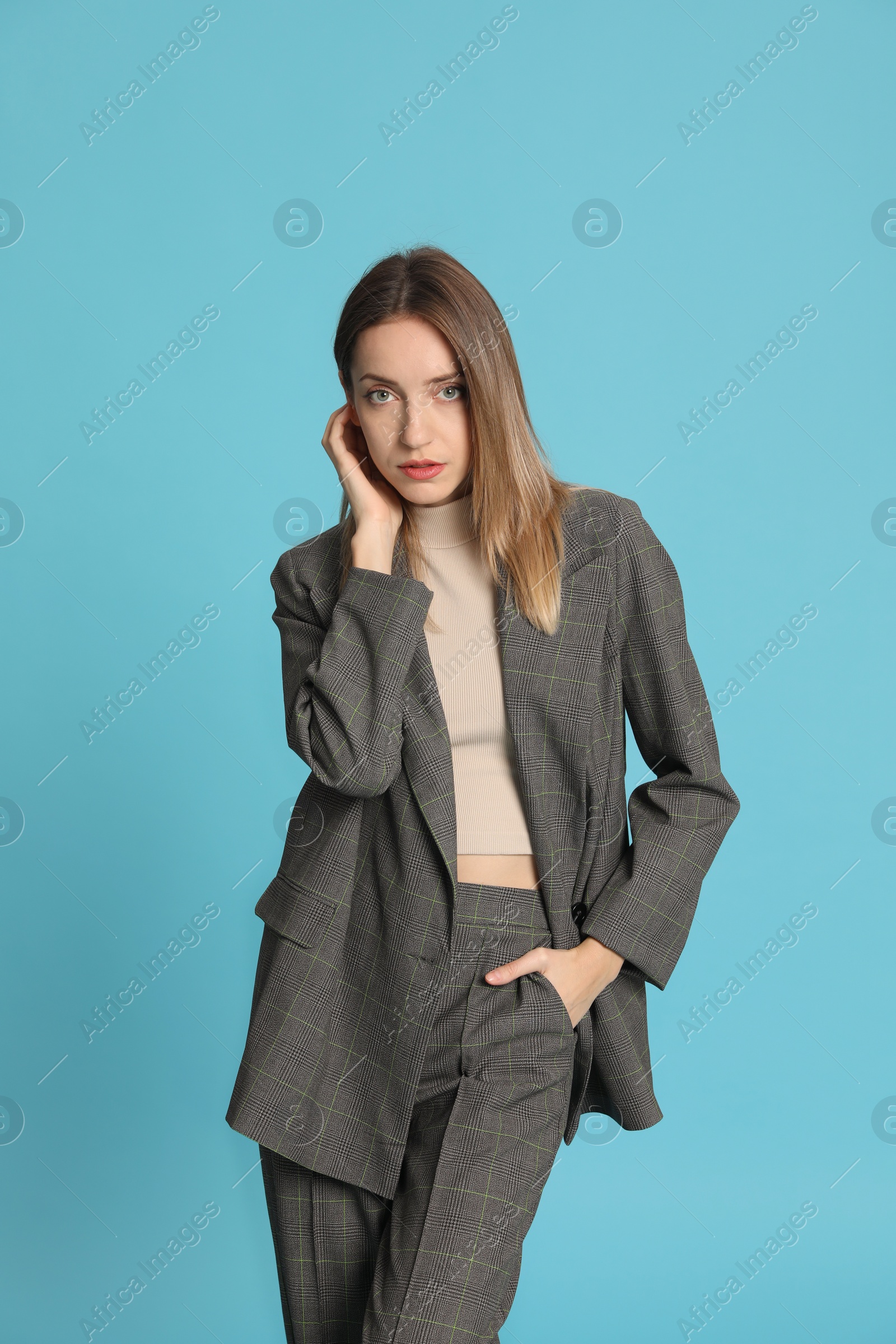 Photo of Portrait of beautiful young woman in fashionable suit on light blue background. Business attire