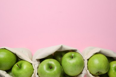 Sacks with ripe green apples on pink background, flat lay. Space for text