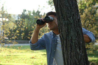 Photo of Jealous man with binoculars spying on ex girlfriend in park