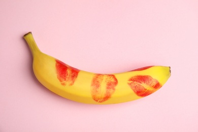 Top view of fresh banana with red lipstick marks on pink background. Oral sex concept