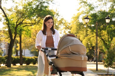 Photo of Young mother walking with her baby in stroller at park on sunny day