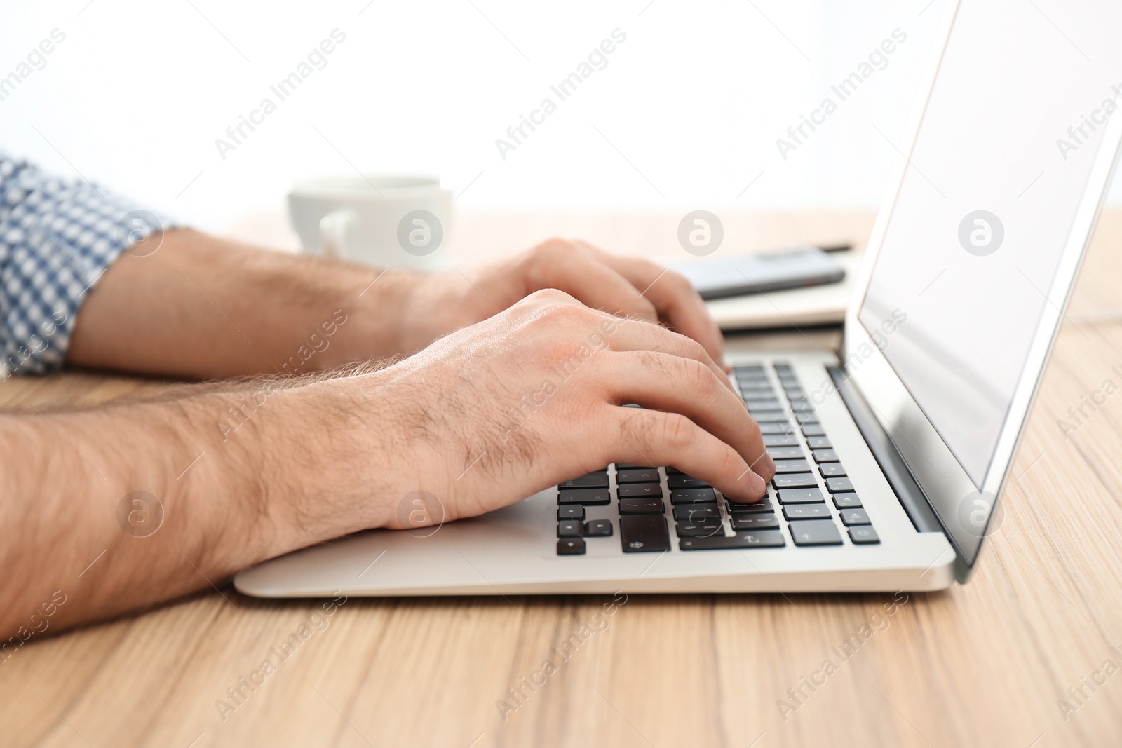 Photo of Man working with modern laptop at wooden table indoors, closeup