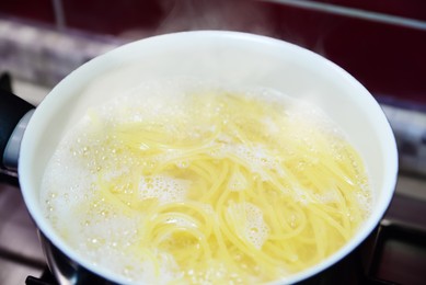 Photo of Cooking pasta in saucepan on stove, closeup