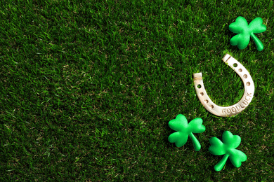 Photo of Flat lay composition with horseshoe on grass, space for text. St. Patrick's Day celebration