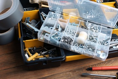 Photo of Boxes with different furniture fittings and tools on wooden table, closeup