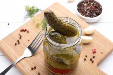 Photo of Tasty pickled cucumbers in jar on wooden board, closeup
