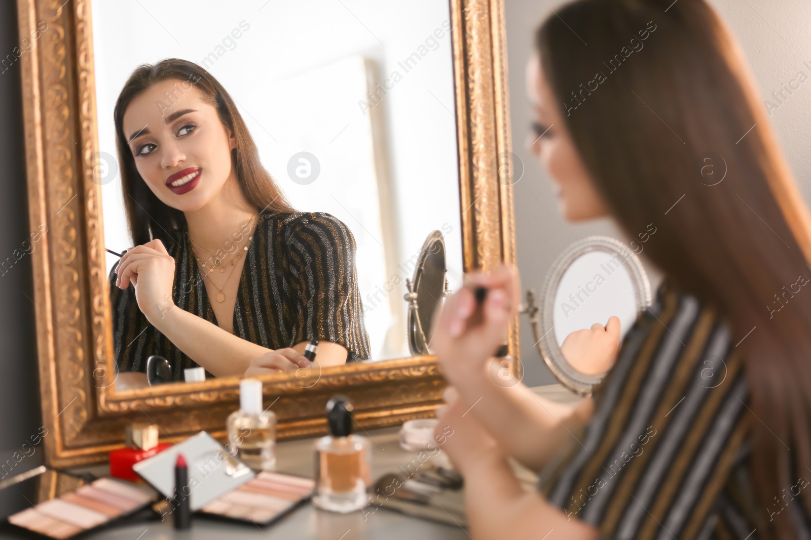 Photo of Portrait of beautiful woman with bright makeup near mirror indoors