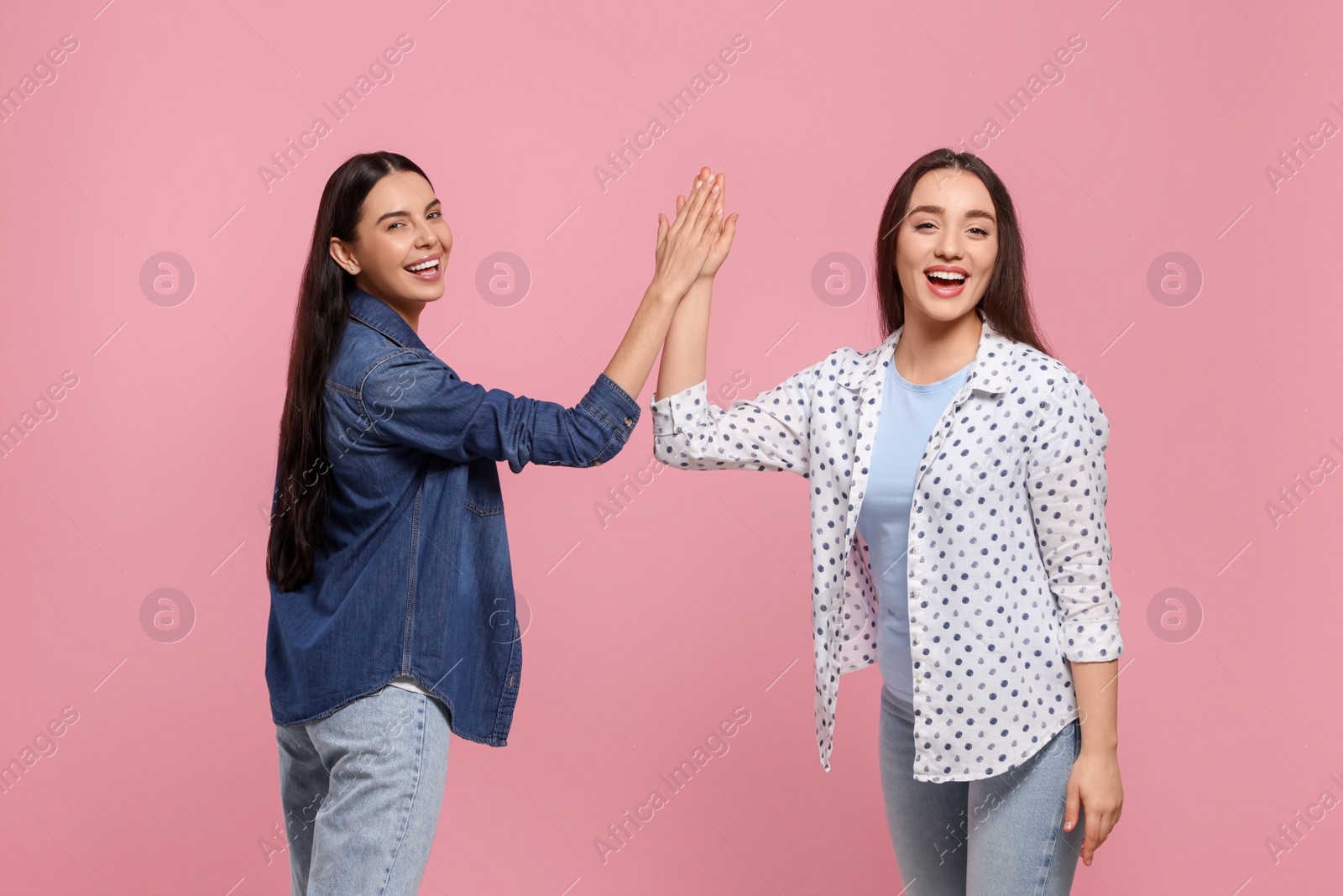 Photo of Women giving high five on pink background