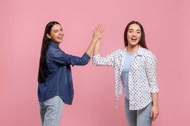 Women giving high five on pink background