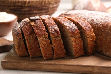 Photo of Cut freshly baked bread on white table, closeup