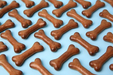Photo of Bone shaped dog cookies on light blue background, closeup