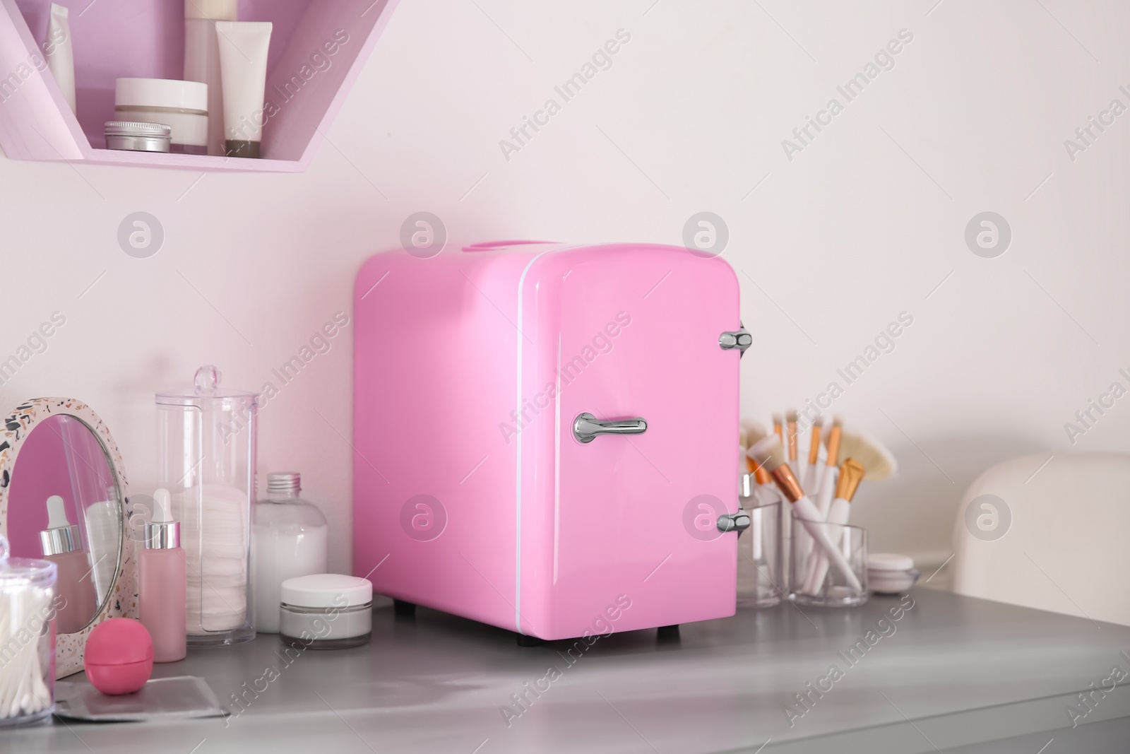 Photo of Cosmetics refrigerator and skin care products on grey vanity table indoors