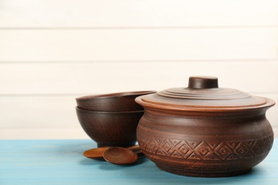 Photo of Set of clay utensils on light blue wooden table. Space for text