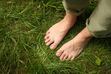 Photo of Woman walking barefoot on green grass outdoors, top view