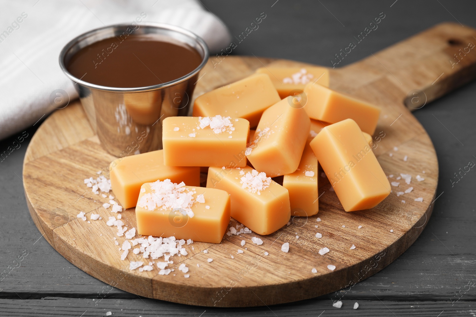 Photo of Yummy caramel candies and sea salt on wooden table, closeup