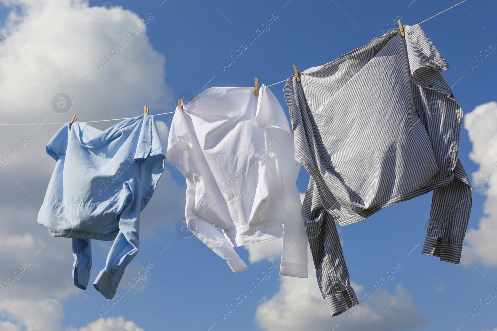 Photo of Clean clothes hanging on washing line against sky. Drying laundry