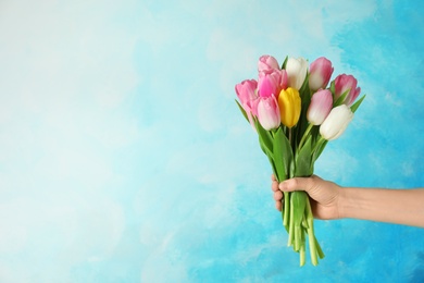 Photo of Girl holding bouquet of beautiful spring tulips on color background, closeup with space for text. International Women's Day