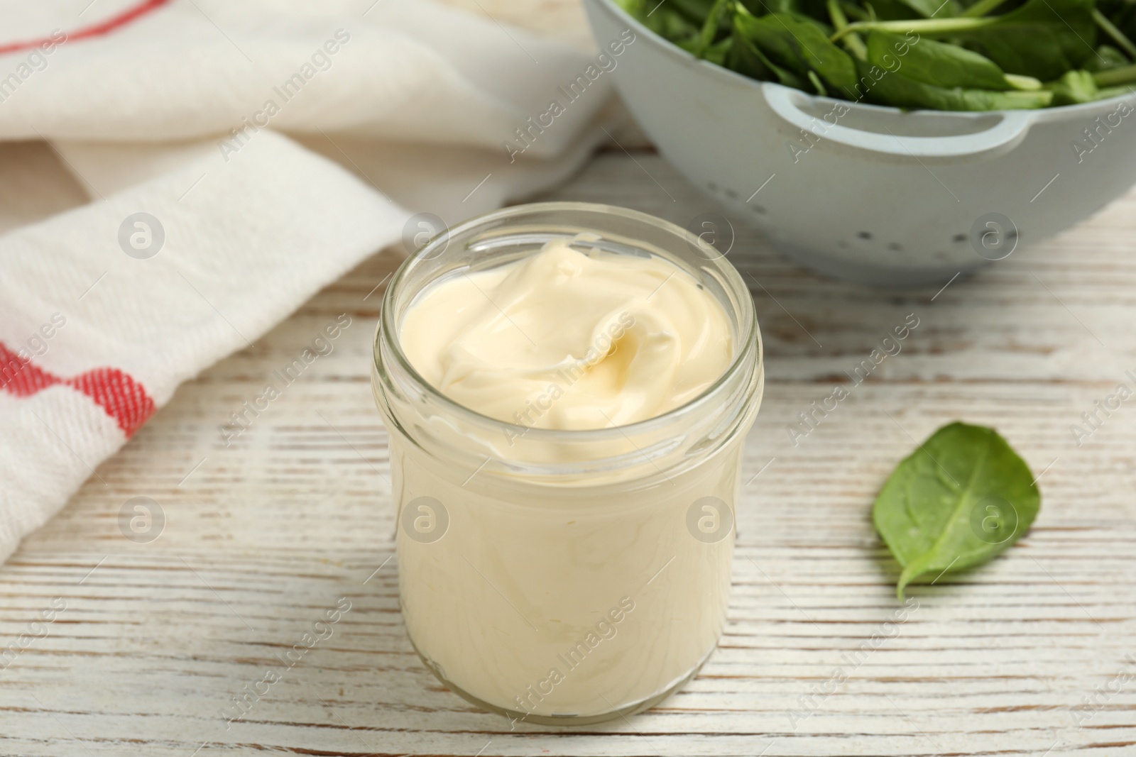 Photo of Jar of delicious mayonnaise and fresh spinach on white wooden table
