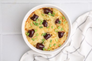 Photo of Tasty sausage casserole with green onions in baking dish on white tiled table, top view