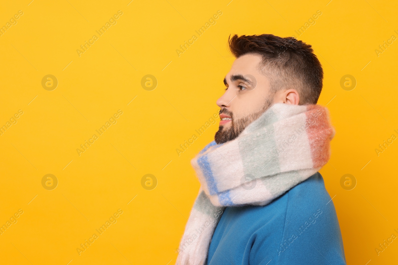 Photo of Handsome man in warm scarf on yellow background. Space for text