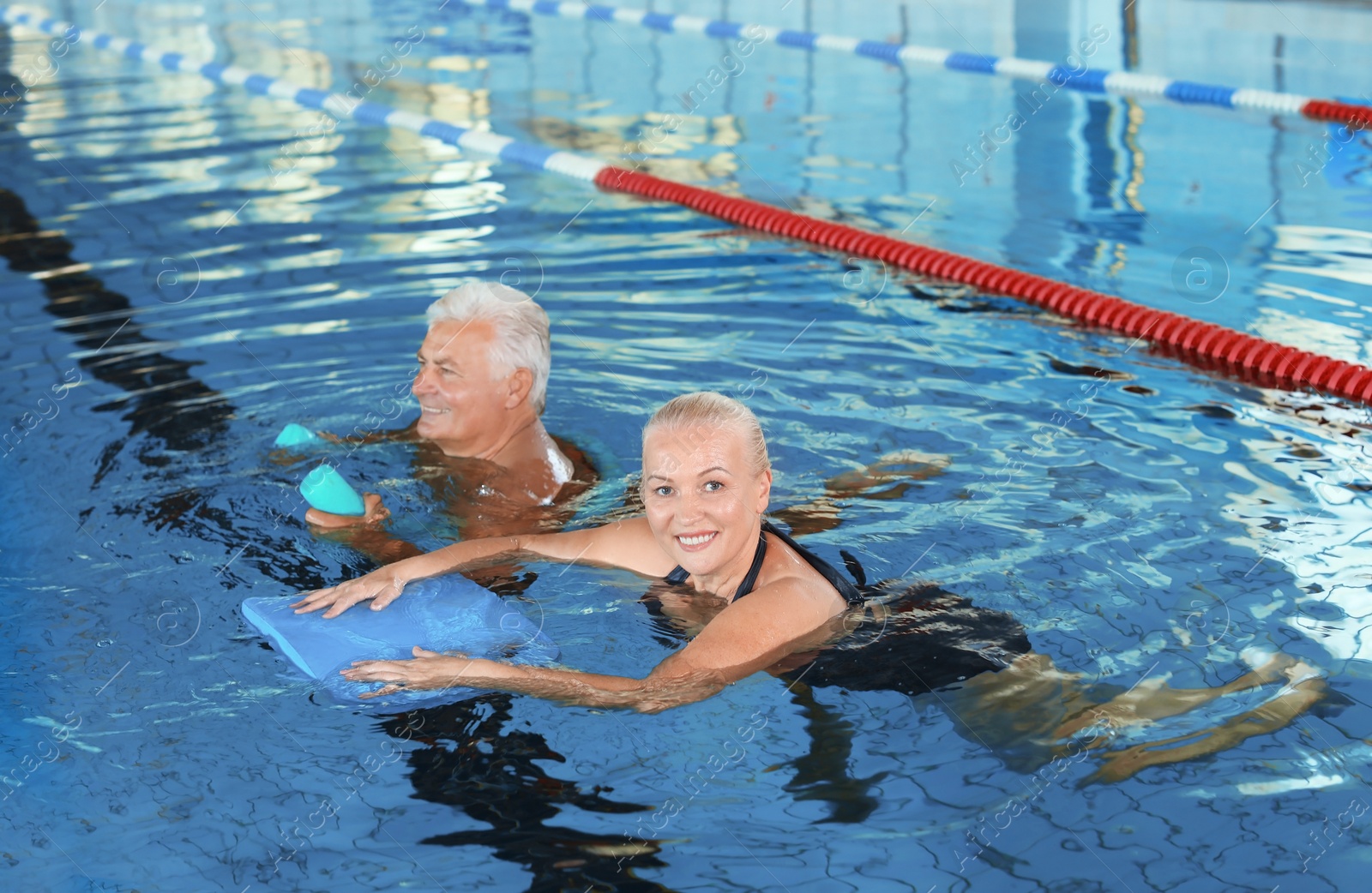 Photo of Sportive senior couple doing exercises in indoor swimming pool