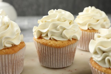 Tasty cupcakes with vanilla cream on table, closeup